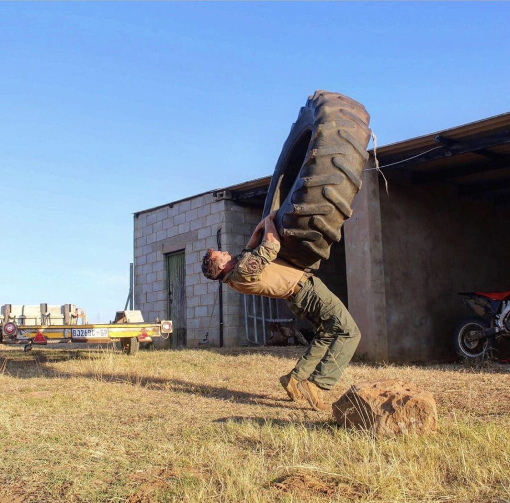 A man flipping a giant truck tire