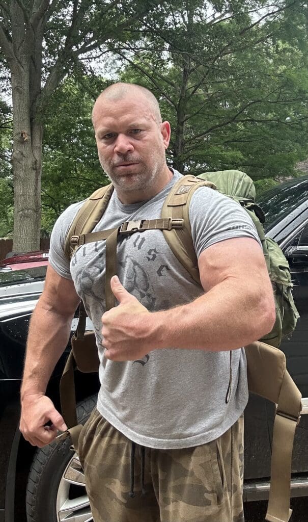 A muscular man wearing a backpack